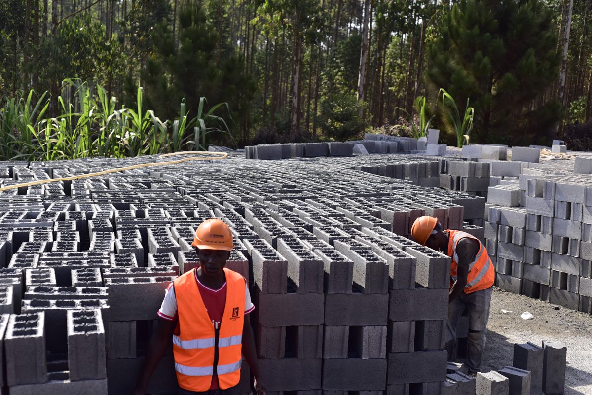 Rows of freshly cast concrete blocks curing in the open yard with a worker in high-visibility clothing