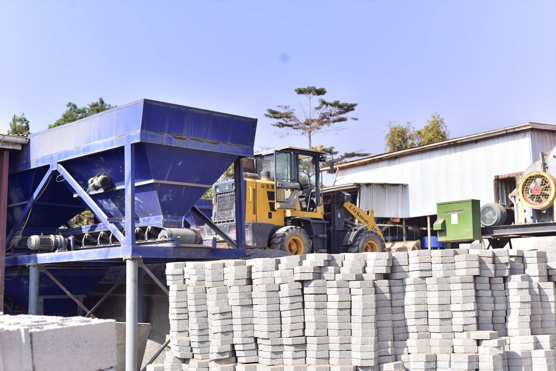 Wide view of the BOKSWA batching plant with a wheel loader and stacked blocks